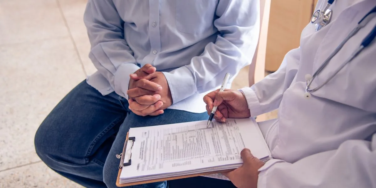Medical provider takes intake notes of an older man in the office.
