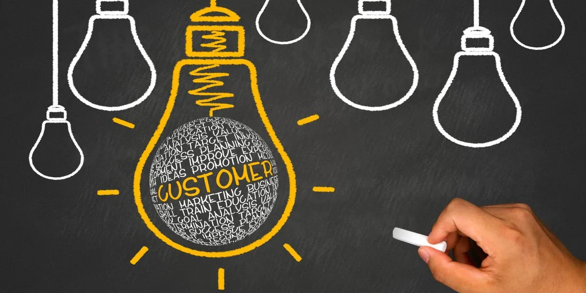 Chalkboard with yellow and white light bulbs drawn on it, with one in yellow that says Customer