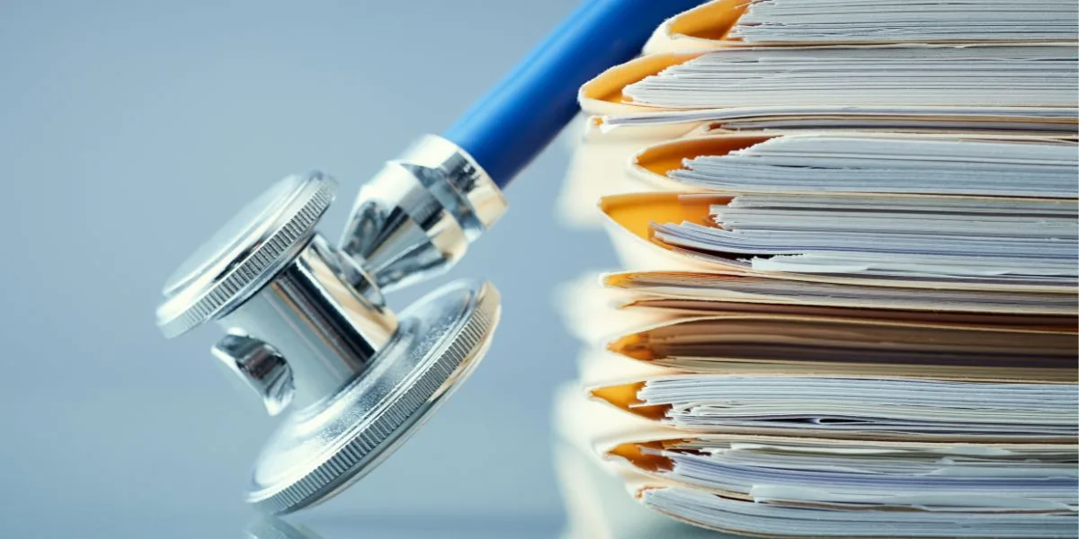 Stethoscope lying over a pile of patient folders.