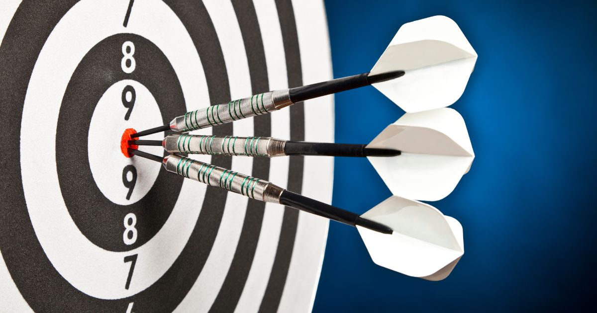 Large target with three darts lined up in the bulls-eye.