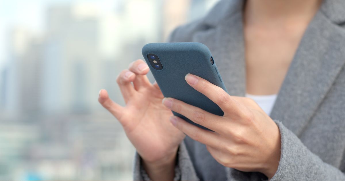 Close up of a professional woman's hands holding her phone and using it.