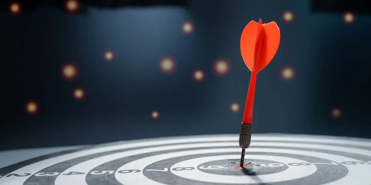 An archery target sits at the bottom of the image with a red dart in the center