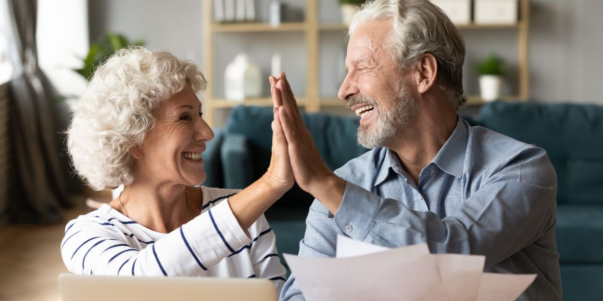 An older couple reviewing documents together at a kitchen table in warm natural light.