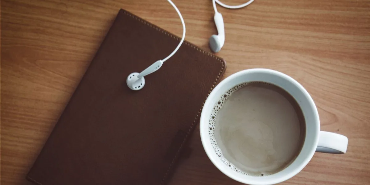Coffee, notebook, and earbuds